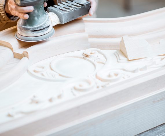 Carpenter grinding joinery product with hand machine, finishing woodwork at the carpentry manufacturing, close-up