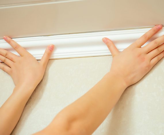humans hands put a ceiling skirting on the ceiling